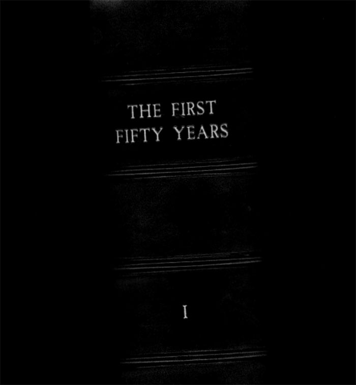 Close-up of a vintage book spine titled The First Fifty Years, related to Jeffrey Epstein's 50th birthday book photos.