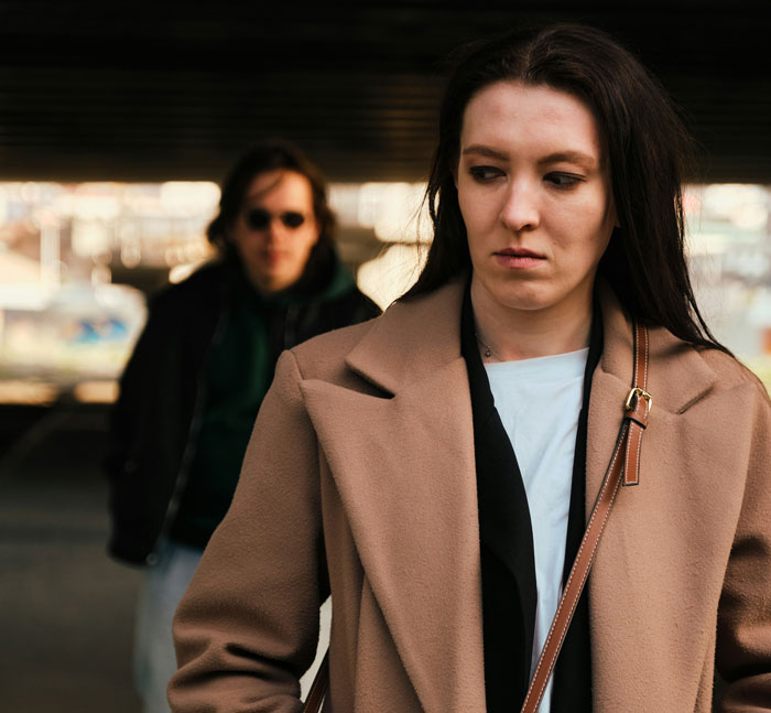 A woman in a brown coat looking away with a man blurred in the background, representing things men didn’t know about women.