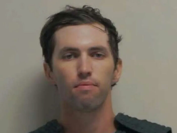 Man with short dark hair and serious expression in a police mugshot related to Charlie Kirk assassin's capture by FBI director. Man with short dark hair and serious expression in a police mugshot related to Charlie Kirk assassin's capture by FBI director.