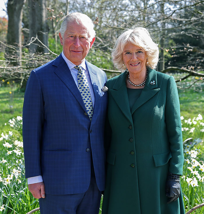 Prince Charles and Queen Camilla smiling outdoors in formal attire during an event related to Queen Camilla&rsquo;s embarrassing gesture.