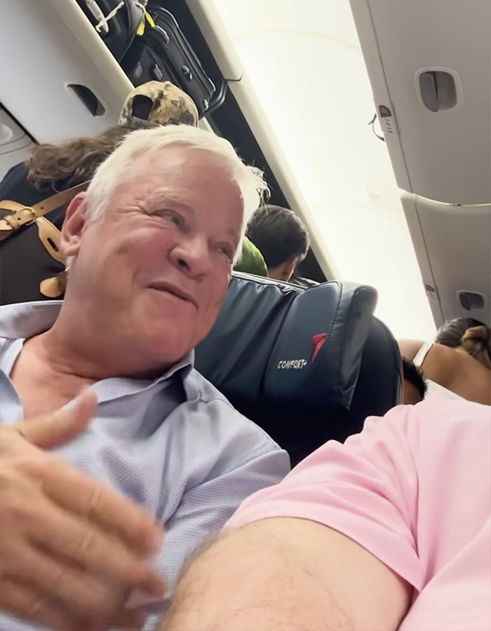 Older man speaking to seatmate on airplane, highlighting incident involving plus-size passenger and flight confrontation. Older man speaking to seatmate on airplane, highlighting incident involving plus-size passenger and flight confrontation.