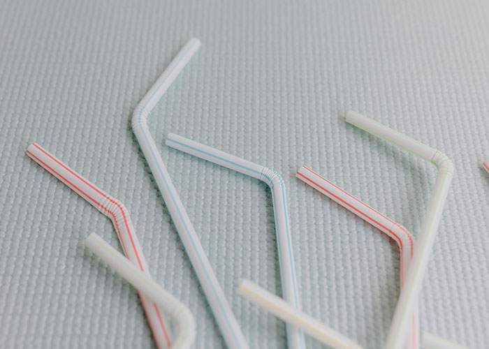 Several bent plastic straws on a textured surface illustrating environmental damage by historical events.