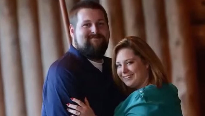 Couple embracing and smiling indoors, relating to woman who didn't know she was pregnant until delivering her third child.