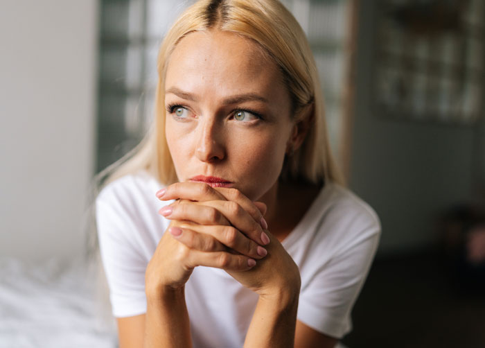 Thoughtful woman sitting indoors, reflecting deeply after giving husband another chance, learning a hard relationship lesson.
