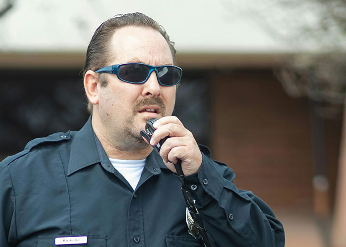 Police officer in sunglasses speaking into a radio, capturing a moment related to criminal fails and law enforcement.