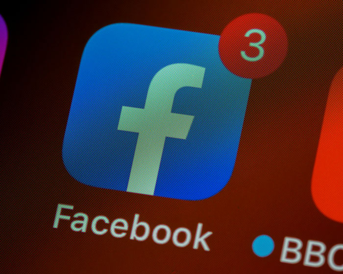 Ícono de la app de Facebook con notificaciones en un teléfono, mostrando uso de teléfonos para descubrir verdades ocultas.