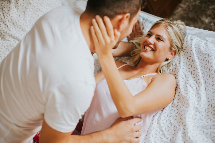Couple sharing a joyful moment on bed, illustrating mind-boggling conversations that make adults wonder how they survived.