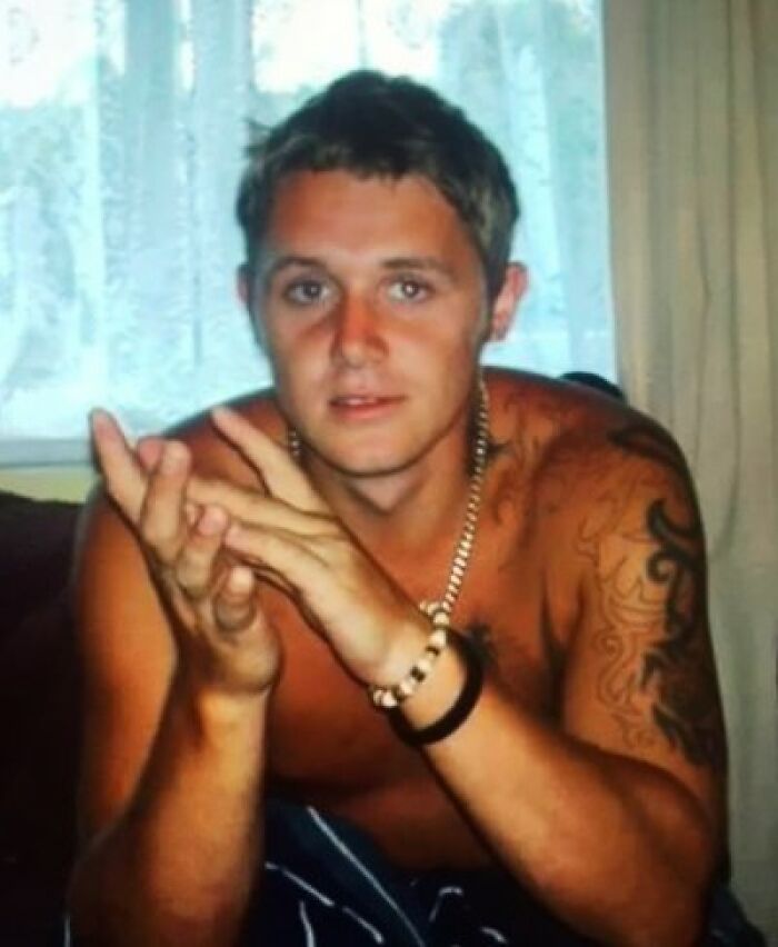 Young man with tattoos and bracelets sitting indoors, representing chilling messages left before going missing cases.