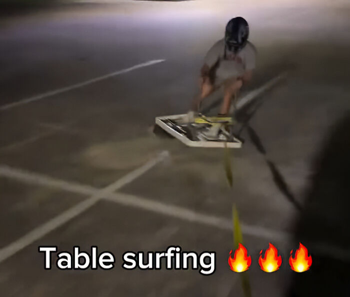 Teen wearing helmet rides table on street at night, illustrating viral TikTok trend causing catastrophic injuries.