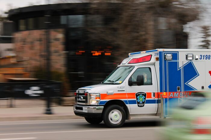 Ambulance speeding on a city street, illustrating chaotic moments related to food delivery drivers' stories.