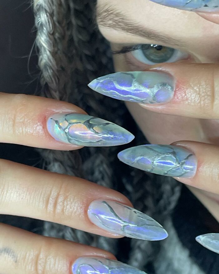 Close-up of iridescent nail designs with abstract patterns on long nails, showcasing unique and creative nail design styles.