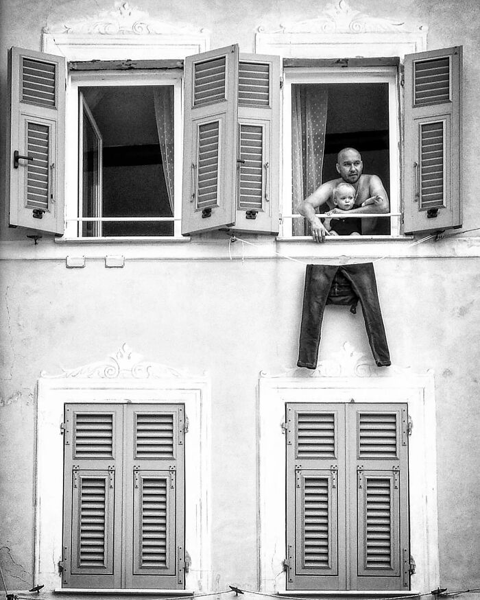 Man and child looking from window with pants hanging outside, a funny coincidence street photo in black and white.