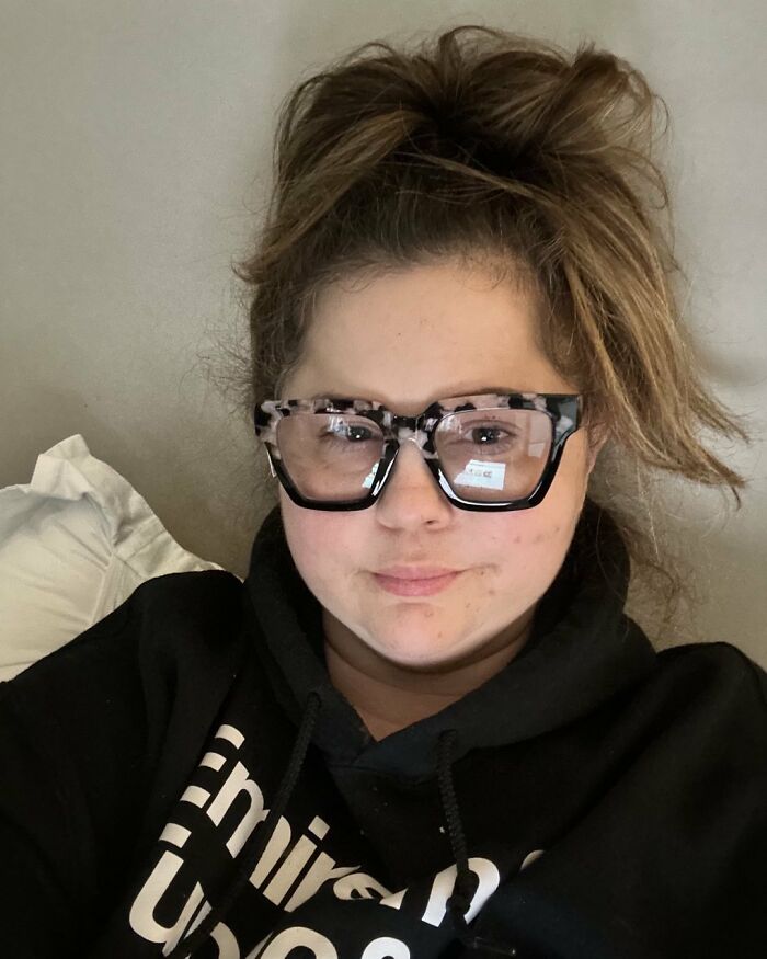 Woman with messy hair and large glasses wearing a black hoodie, representing Selena Gomez snubbing her mom at wedding event. Woman with messy hair and large glasses wearing a black hoodie, representing Selena Gomez snubbing her mom at wedding event.