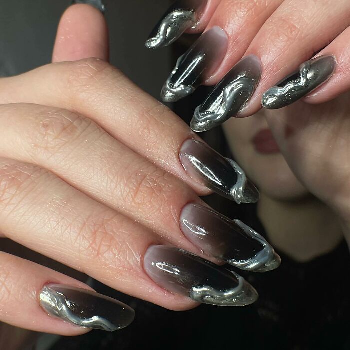 Metallic and black 3D swirl nail designs on long almond-shaped nails showcasing bold nail designs.