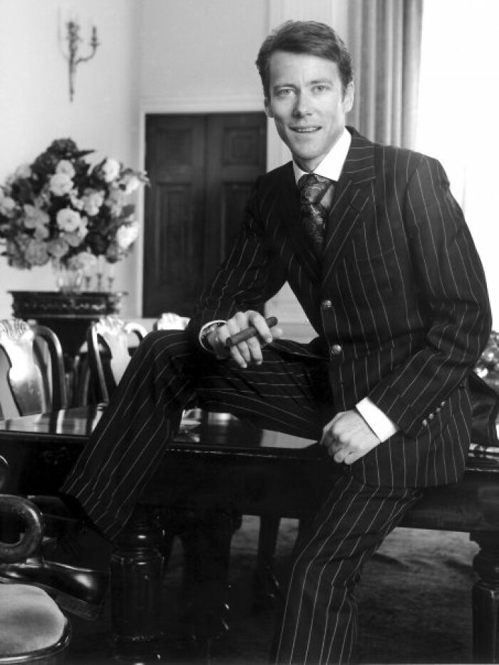 Man in a pinstripe suit sitting on a table holding a cigar, illustrating famous fraud cases concept.