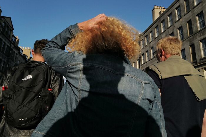 Group of people walking on a sunny street, capturing the funny side of life in brilliant street photos.