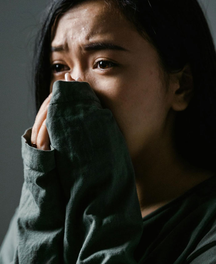 Woman worried and distressed, covering her mouth, reflecting anxiety about creepy Airbnb host texts.