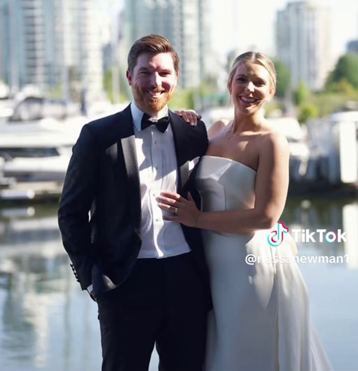 Woman in a wedding dress and man in tuxedo smiling outdoors by waterfront, considering recreating wedding photos.
