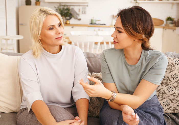 Two women having a serious conversation on a couch, illustrating conflict in an open marriage situation.