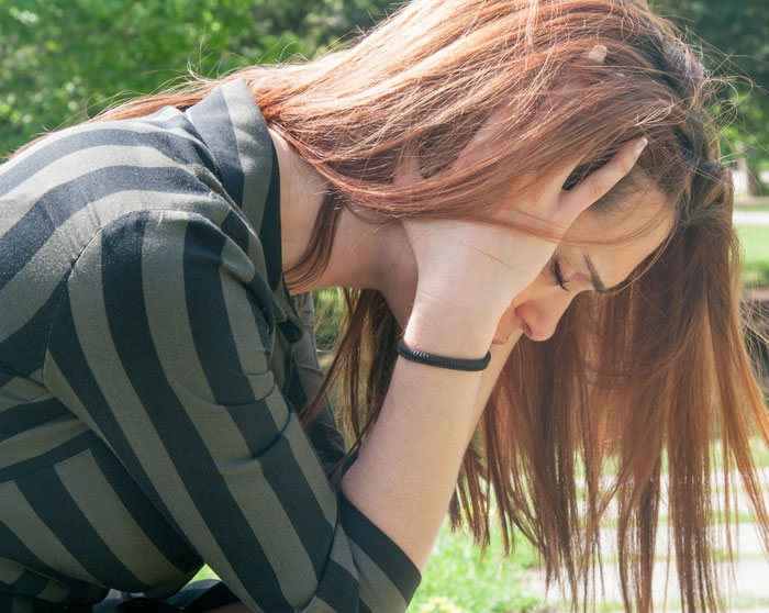 Teen girl suffering an allergic reaction, holding her head outdoors, reflecting distress from a friend’s house incident. Teen girl suffering an allergic reaction, holding her head outdoors, reflecting distress from a friend’s house incident.