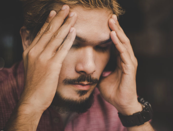 Man with beard holding his head in stress, illustrating a lesson learned the hard way about giving another chance.