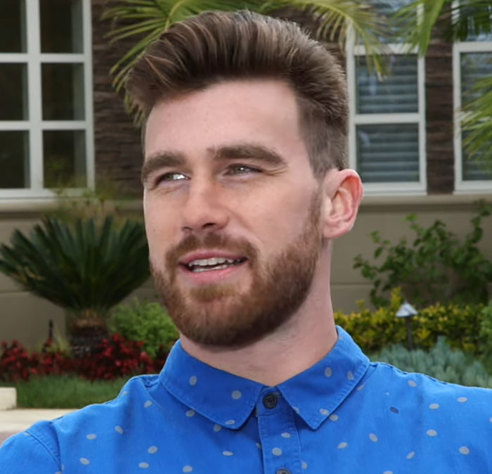 Man in a blue shirt outdoors, discussing Travis Kelce&rsquo;s answer about Taylor Swift in resurfaced video that stuns fans.