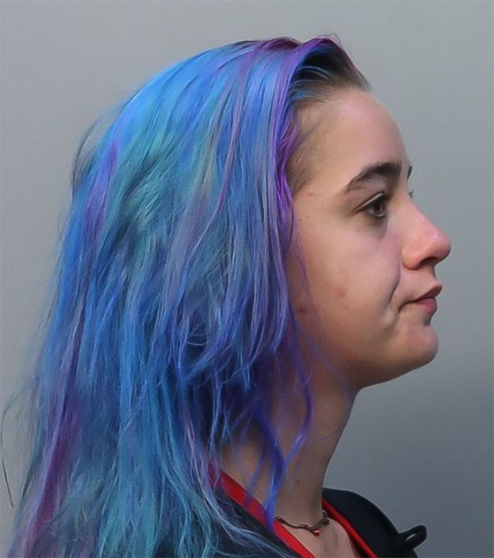 Profile view of a young woman with blue and purple hair, related to a couple arrested for hotboxing in a car.
