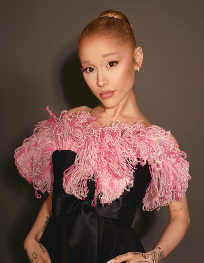 Ariana Grande posing in a black dress with pink feathered details amid Ethan Slater breakup rumors. Ariana Grande posing in a black dress with pink feathered details amid Ethan Slater breakup rumors.