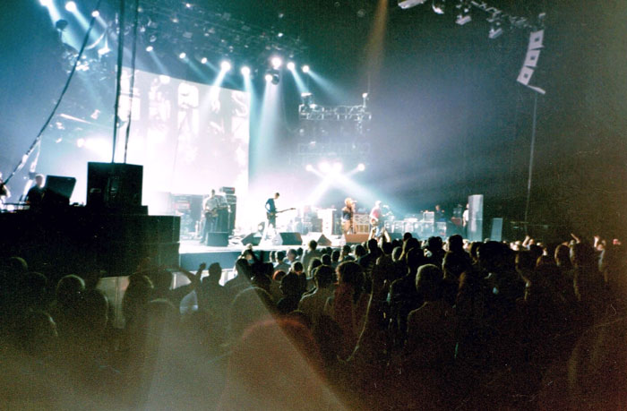 Crowded live concert with band performing on stage and fans watching, illustrating concerts fans wish they'd skipped.