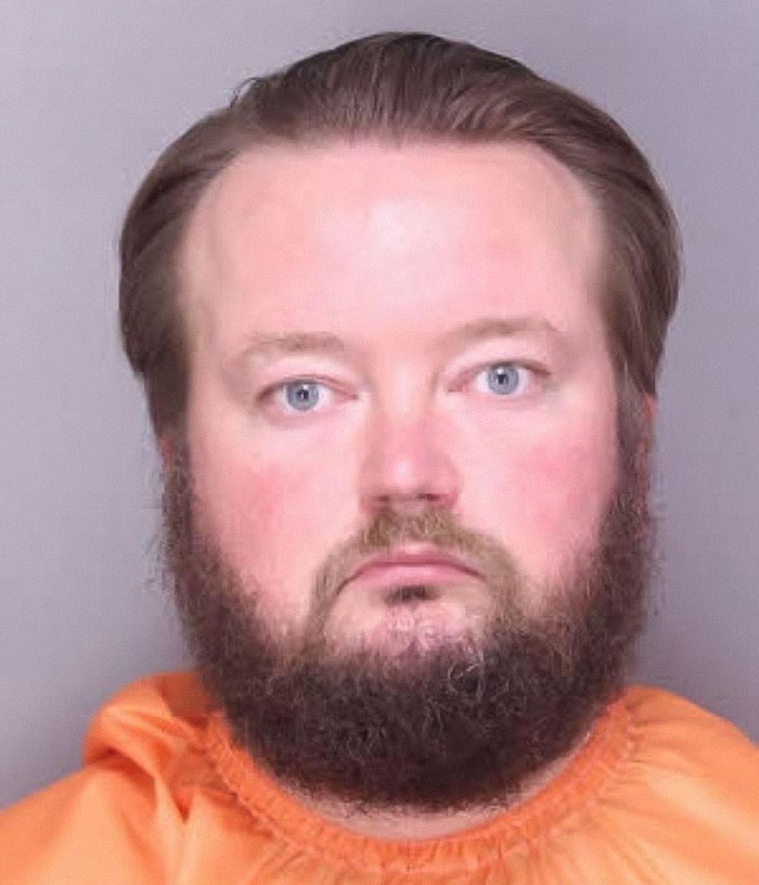 Mugshot of a teacher arrested for using poop spray around school causing sickness and costly repairs.