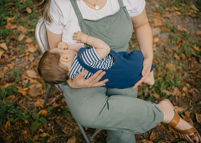 Mother breastfeeding baby outdoors, highlighting health risks of breastfeeding stigma and the challenges of pumping breast milk.