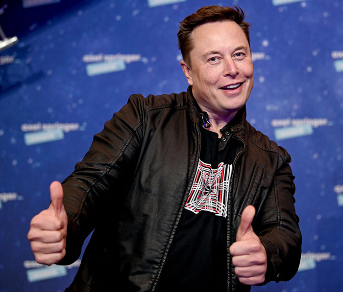 Elon Musk giving thumbs up at an event, relating to hypocrisy accusations after reposting viral church message.