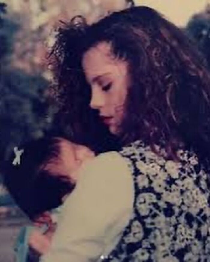 Young woman with curly hair holding a baby closely, capturing a tender moment related to Selena Gomez and family news. Young woman with curly hair holding a baby closely, capturing a tender moment related to Selena Gomez and family news.