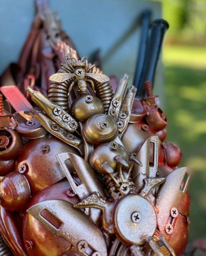 Sculpture of a dragon head made from recycled trash materials, showcasing stunning animal sculptures art outdoors.