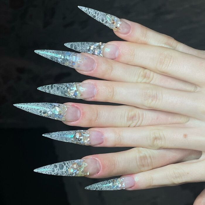 Clear stiletto nail designs with iridescent embellishments and textured details showcasing bold nail design creativity.
