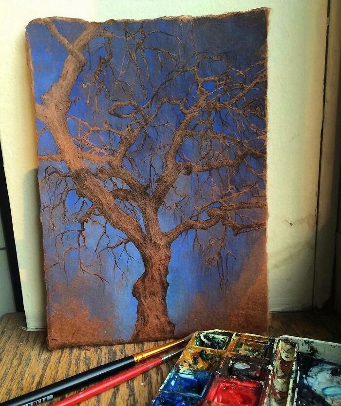 Detailed painting of a bare tree on textured paper by Dina Brodsky showcasing the beauty of the natural world with paints and brushes nearby.