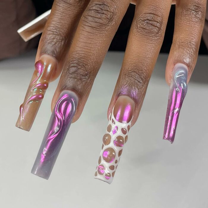 Close-up of creative long nail designs with 3D effects and iridescent colors showcasing unique nail design styles.