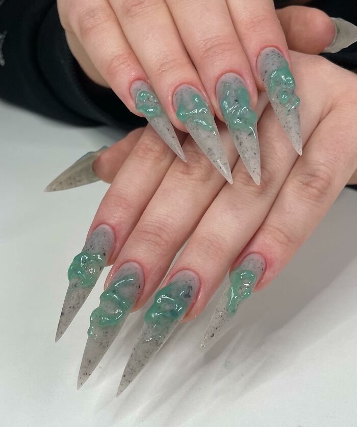Long pointed nail designs with green 3D gel accents on a gray speckled base, showcasing unique and creative nail art.