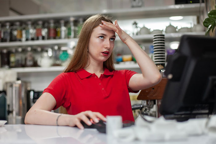 Salon employee in red shirt refusing to sell box dye, showing frustration while working at the counter. Salon employee in red shirt refusing to sell box dye, showing frustration while working at the counter.