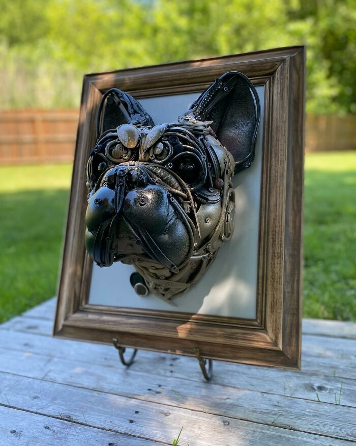 Dog head sculpture made from recycled metal parts displayed in a wooden frame, showcasing trash turned into stunning animal art.
