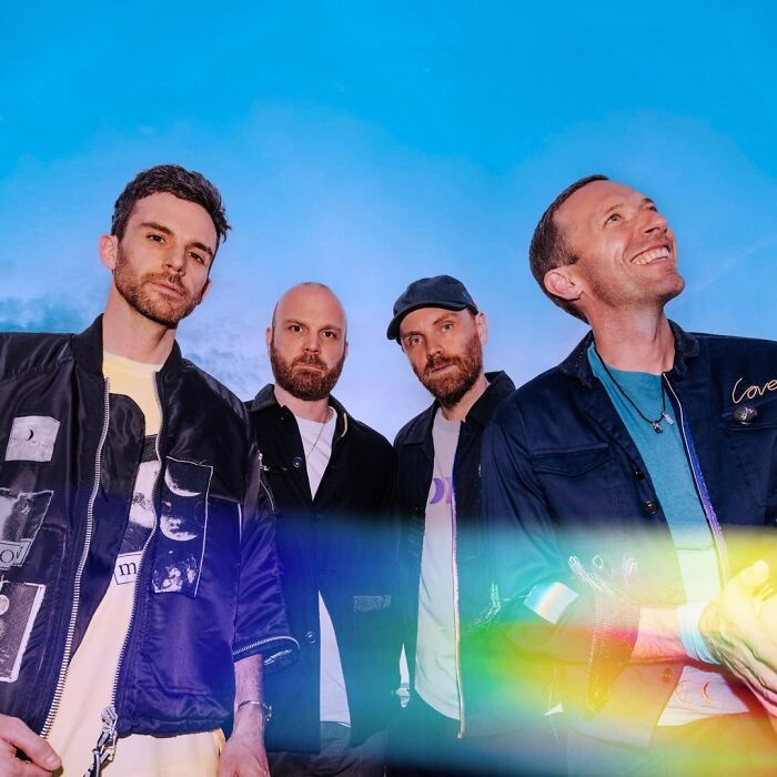 Coldplay band members posing outdoors against a blue sky, related to Kristin Cabot Coldplay scandal news discussion.