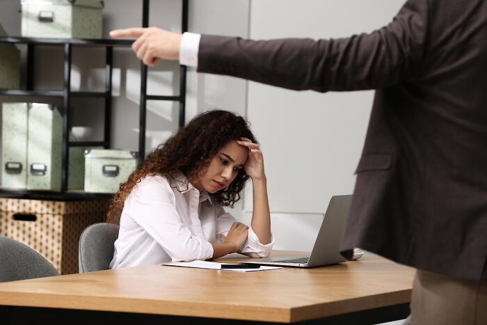 Woman looking stressed at laptop while a man points, illustrating discovery of partners' and spouses' secret stories online.