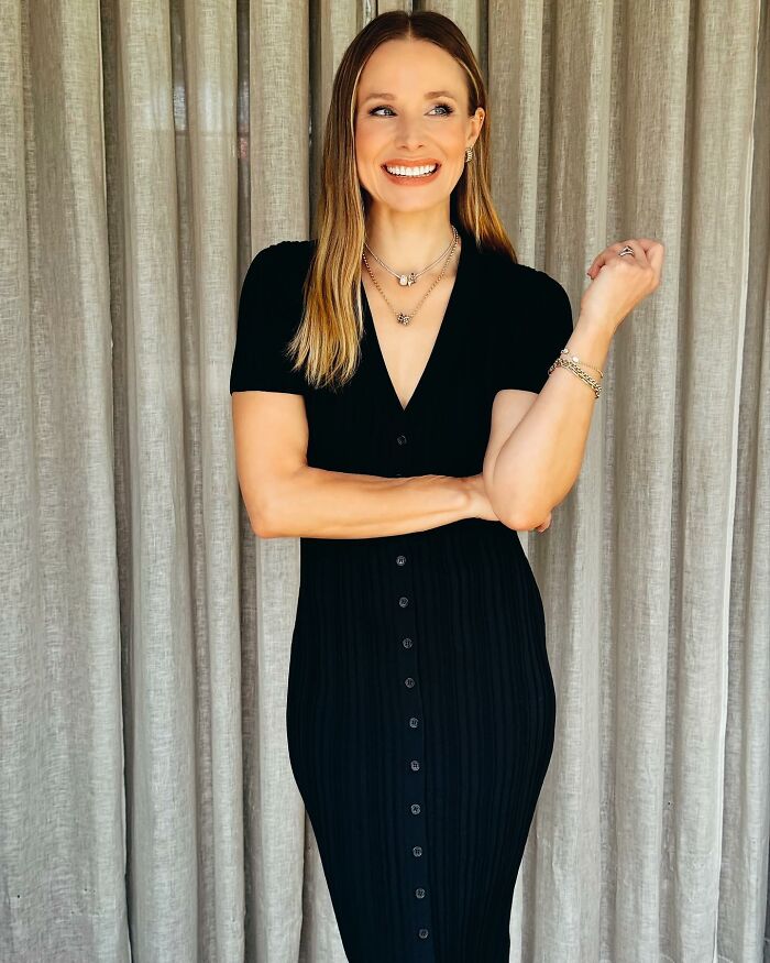 Kristen Bell in a black dress smiling and posing, highlighting a simple biohacking trick to stay fit supported by experts.