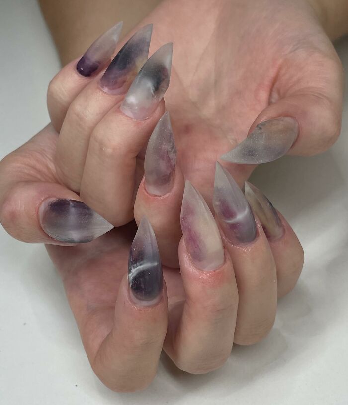 Translucent matte stiletto nail designs with smoky purple and gray accents showcasing bold nail design trends.