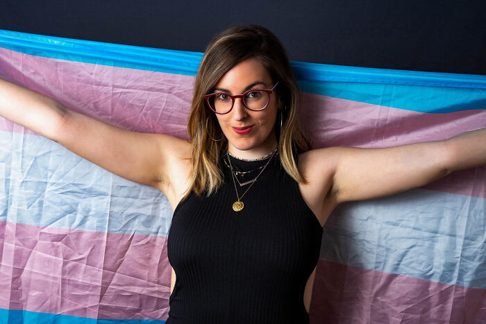 Young woman holding a transgender pride flag, symbolizing identity while discovering partners' secret stories online.