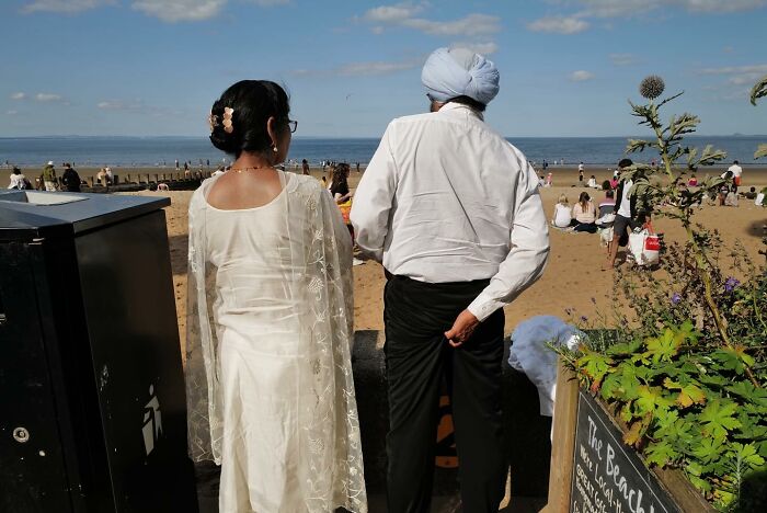 Couple dressed in traditional clothing at a beach, part of brilliant street photos capturing the funny side of life.
