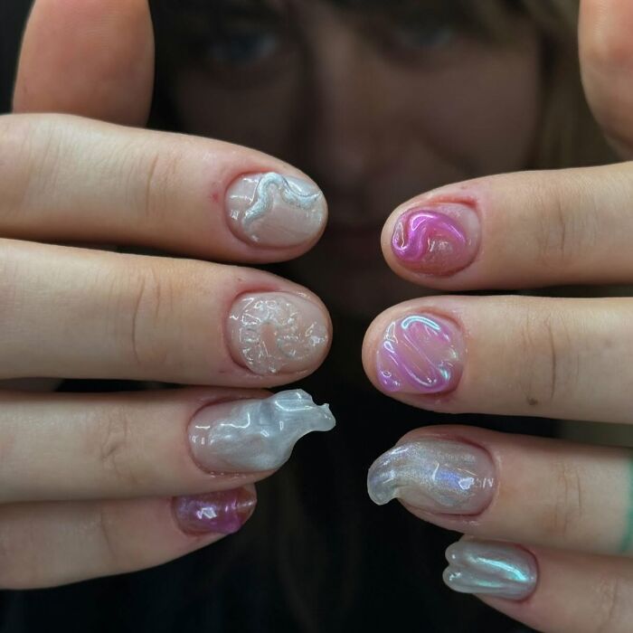 Close-up of unique 3D nail designs with glossy, wavy textures in pink and silver, showcasing creative nail designs.