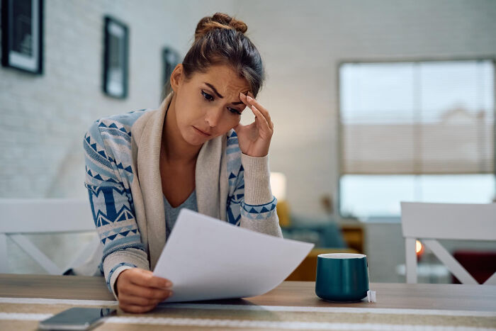Woman reading paper with a concerned look, illustrating life-changing sentences that left a strong impact on her.
