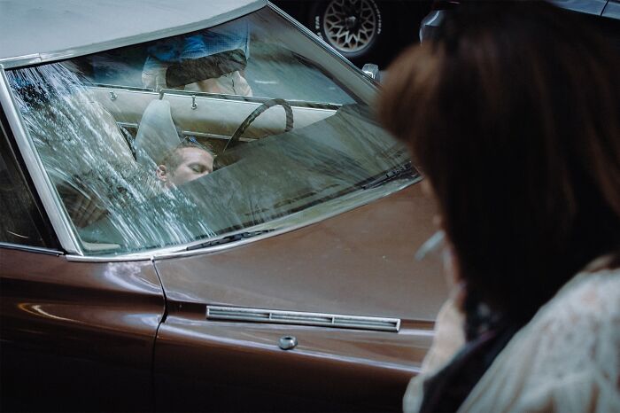 Man resting inside a vintage car captured in striking street photos that feel like movie stills with cinematic lighting.