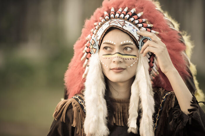 Woman wearing traditional Native American headdress and face paint, symbolizing shocking family secrets uncovered.
